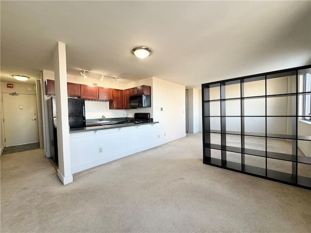 kitchen featuring black appliances, rail lighting, light carpet, and sink