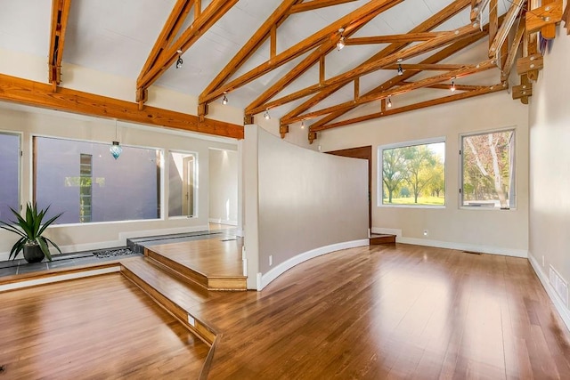 unfurnished living room with wood-type flooring, high vaulted ceiling, and beam ceiling