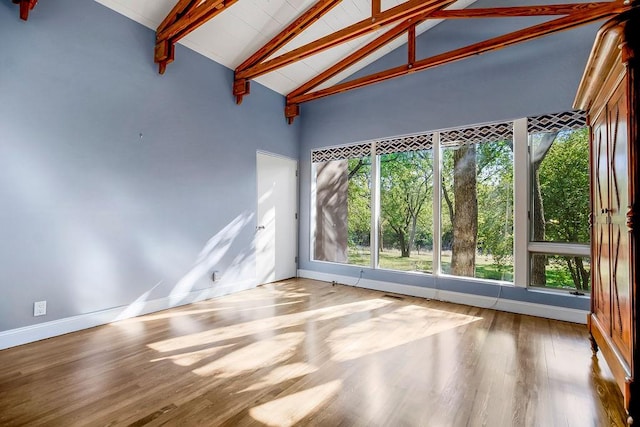 unfurnished sunroom featuring vaulted ceiling with beams