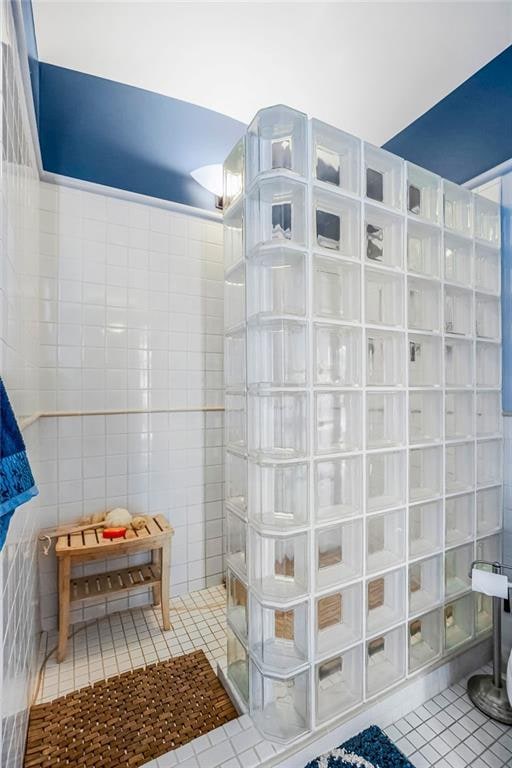 bathroom featuring a shower, tile patterned flooring, and tile walls