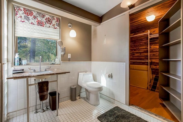 bathroom featuring tile patterned flooring, toilet, tile walls, and sink