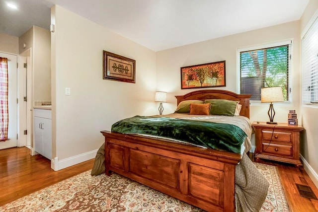 bedroom featuring ensuite bathroom and light hardwood / wood-style flooring