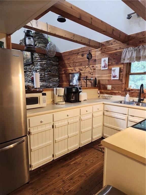 kitchen featuring pendant lighting, sink, wooden walls, dark hardwood / wood-style floors, and stainless steel fridge