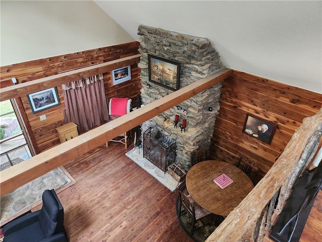 sitting room with a stone fireplace, wood-type flooring, and wooden walls