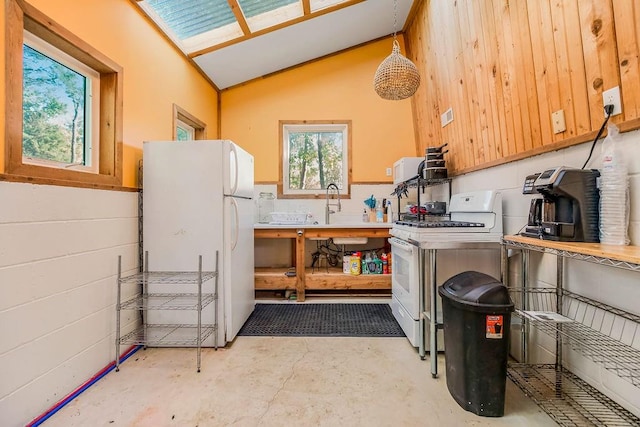 kitchen with vaulted ceiling, wood walls, hanging light fixtures, and white appliances