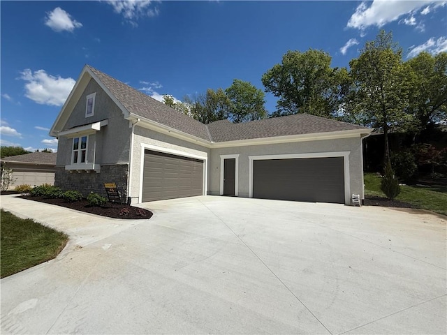 view of side of property featuring a garage, stucco siding, a shingled roof, concrete driveway, and stone siding