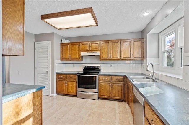 kitchen with backsplash, sink, stainless steel appliances, and a textured ceiling