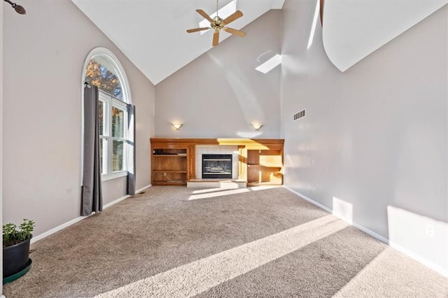 unfurnished living room featuring carpet, high vaulted ceiling, ceiling fan, and a tiled fireplace