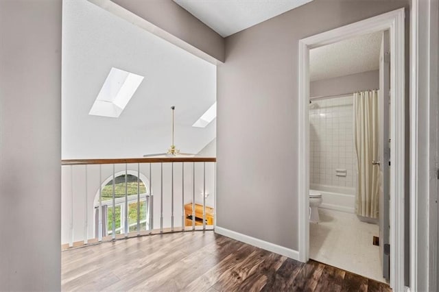 hall with hardwood / wood-style floors and a skylight