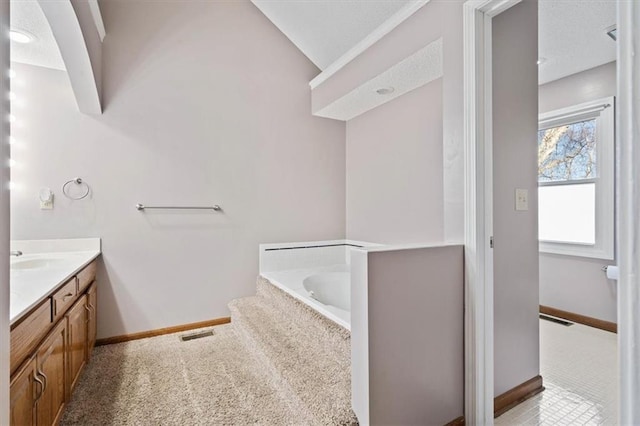 bathroom with tiled tub and vanity