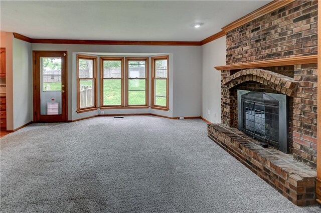 unfurnished living room featuring a brick fireplace, carpet floors, and ornamental molding