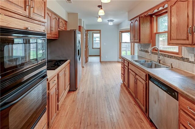 kitchen featuring sink, decorative light fixtures, black appliances, light hardwood / wood-style floors, and backsplash