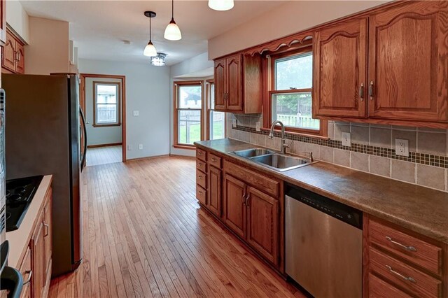 kitchen featuring sink, light hardwood / wood-style flooring, dishwasher, pendant lighting, and backsplash