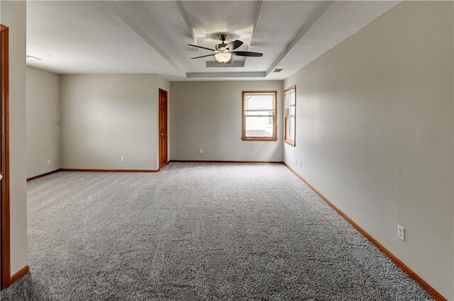 empty room featuring ceiling fan, a raised ceiling, and carpet floors