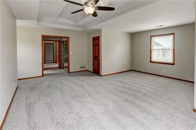 carpeted empty room featuring a raised ceiling and ceiling fan