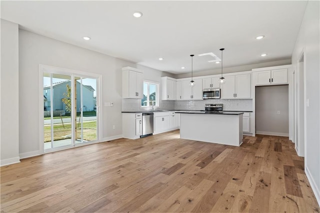 kitchen featuring white cabinetry, hanging light fixtures, stainless steel appliances, and light hardwood / wood-style flooring