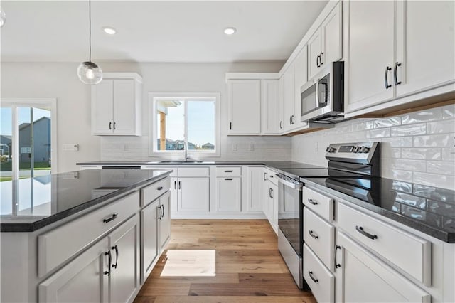 kitchen featuring light wood-type flooring, tasteful backsplash, stainless steel appliances, sink, and white cabinetry