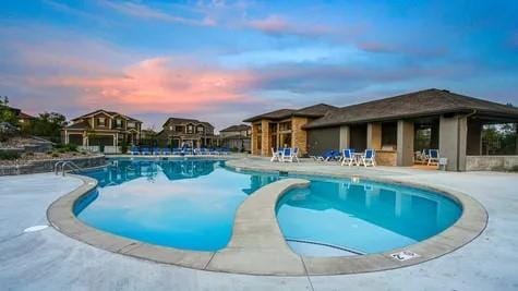 pool at dusk with a patio area