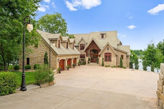 view of front of home featuring driveway, stone siding, a garage, and stucco siding