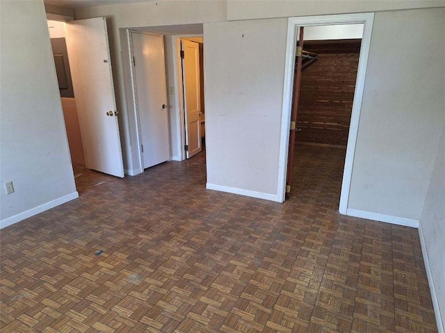 unfurnished bedroom featuring dark parquet flooring and a closet