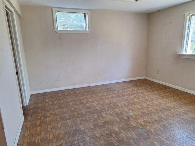 spare room featuring a healthy amount of sunlight and dark parquet floors