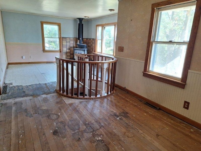 living room featuring wood-type flooring, plenty of natural light, and a wood stove