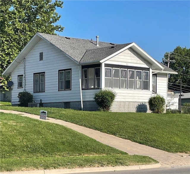 view of side of property with a yard and a shingled roof