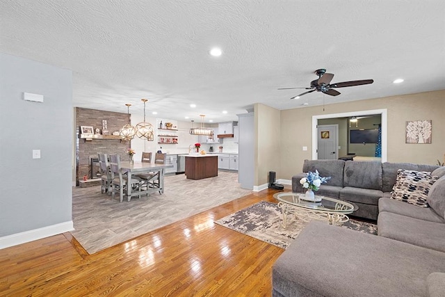 living room featuring a textured ceiling, ceiling fan, and light wood-type flooring