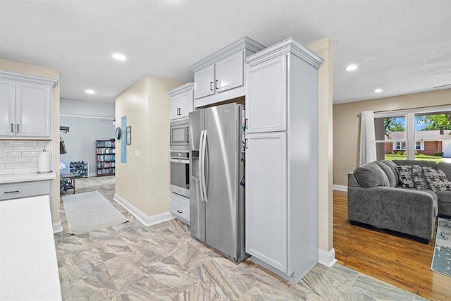 kitchen featuring appliances with stainless steel finishes, light hardwood / wood-style flooring, white cabinetry, and decorative backsplash