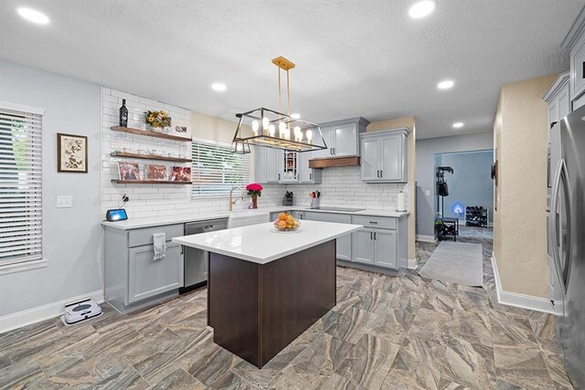 kitchen featuring gray cabinets, decorative light fixtures, tasteful backsplash, stainless steel appliances, and a center island