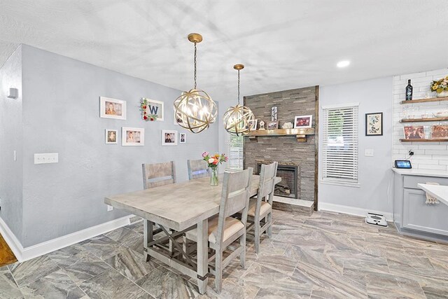 tiled dining area featuring an inviting chandelier and a stone fireplace