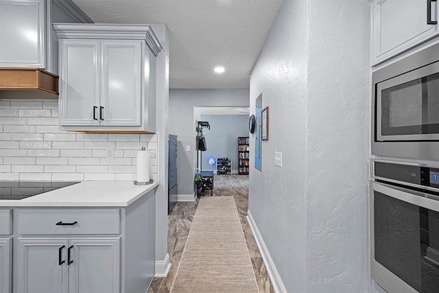 kitchen featuring light hardwood / wood-style flooring, tasteful backsplash, stainless steel appliances, gray cabinetry, and custom range hood