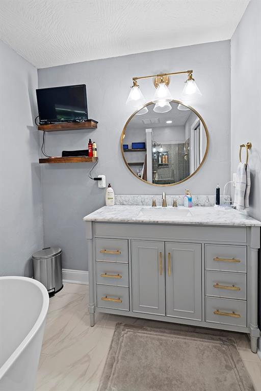 bathroom featuring vanity, tile patterned floors, and a tub to relax in