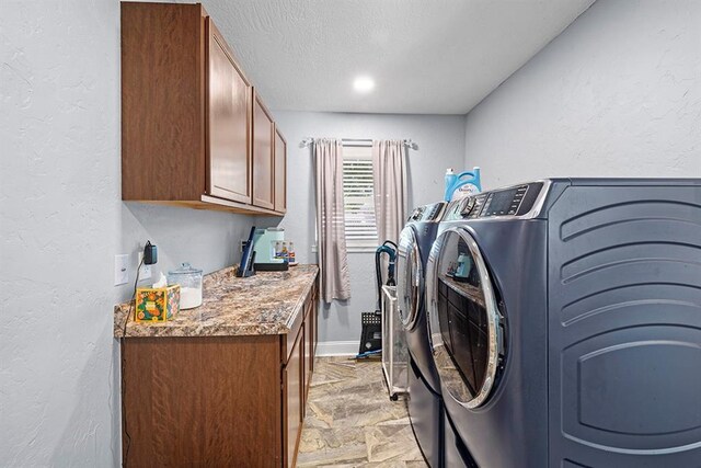 clothes washing area featuring cabinets, light tile patterned floors, and washing machine and clothes dryer