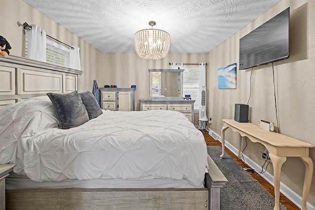 bedroom featuring dark wood-type flooring, a textured ceiling, and an inviting chandelier