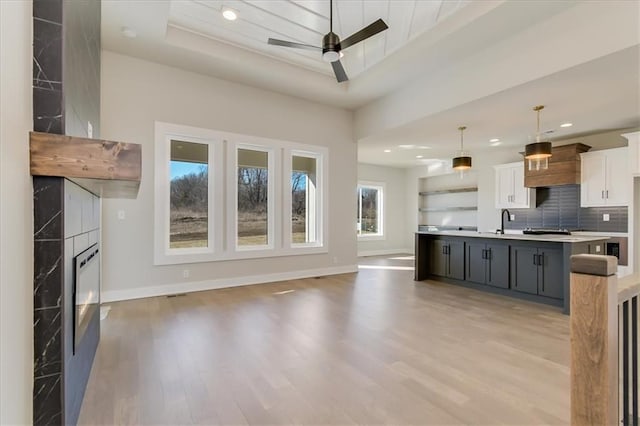 kitchen featuring decorative light fixtures, light countertops, open floor plan, white cabinetry, and an island with sink