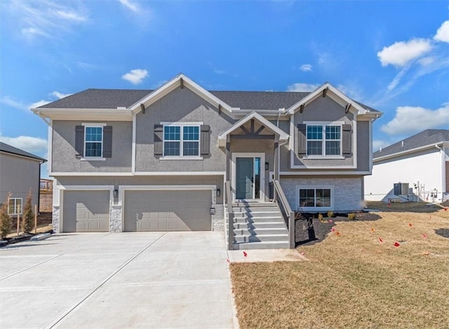 raised ranch with stucco siding, concrete driveway, an attached garage, a front yard, and stone siding