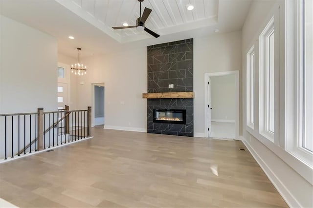 unfurnished living room with plenty of natural light, wood finished floors, baseboards, and a high end fireplace