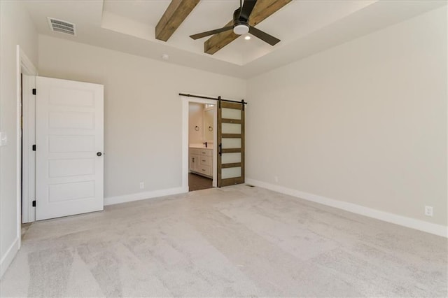 unfurnished bedroom with beam ceiling, visible vents, baseboards, and a barn door