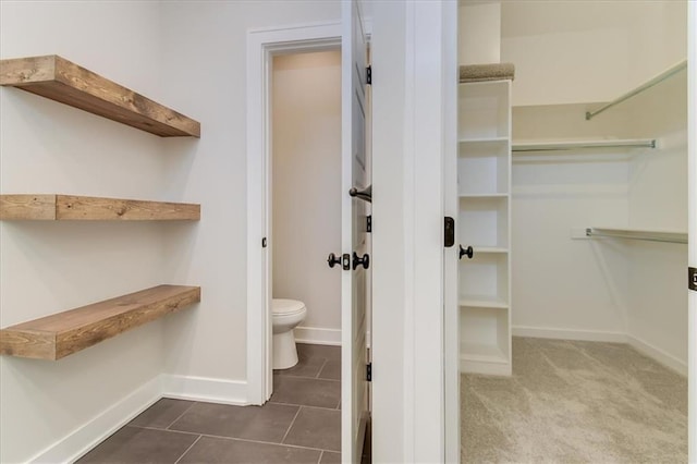 spacious closet featuring dark tile patterned flooring and dark carpet