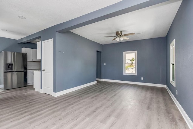 unfurnished living room featuring ceiling fan and light wood-type flooring