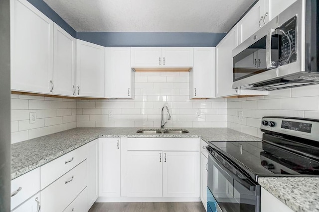 kitchen featuring sink, white cabinetry, electric range oven, tasteful backsplash, and light stone countertops