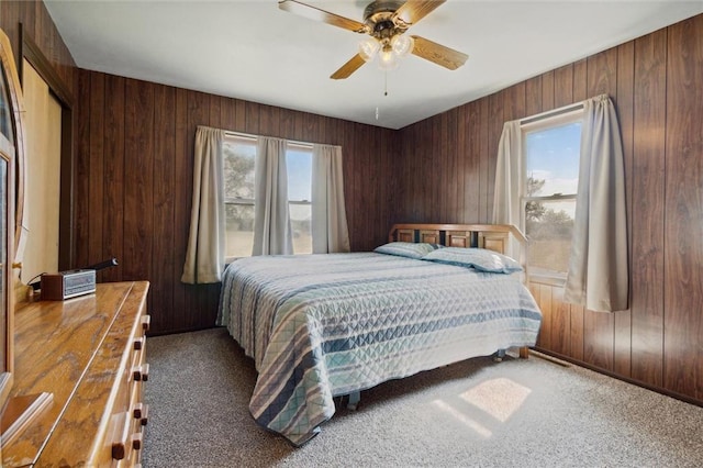 carpeted bedroom featuring ceiling fan and wooden walls