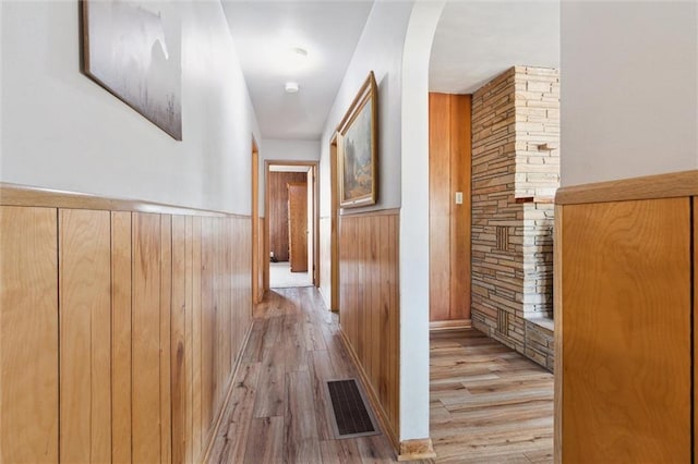 hall featuring wooden walls and light hardwood / wood-style flooring