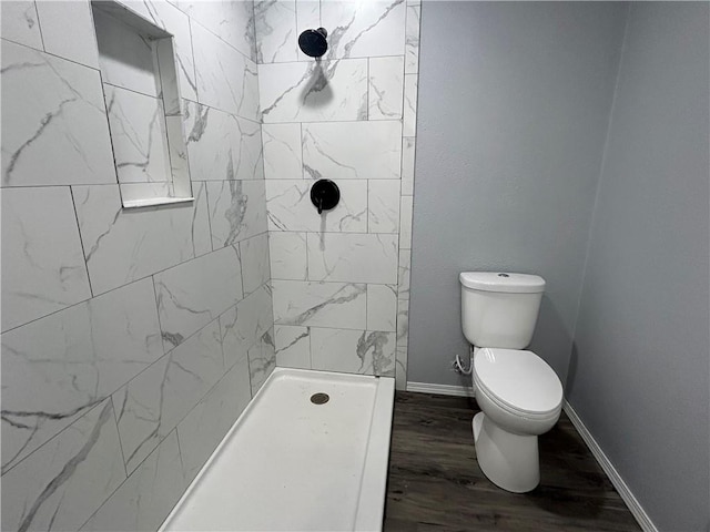 bathroom featuring tiled shower, toilet, and hardwood / wood-style floors