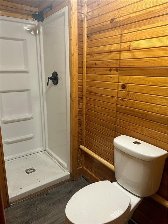 bathroom with a shower, toilet, wood walls, and hardwood / wood-style flooring