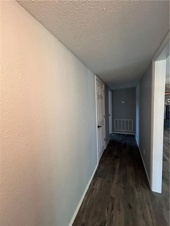 hall featuring a textured ceiling and dark hardwood / wood-style floors