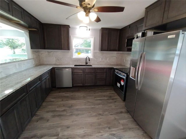 kitchen featuring wood-type flooring, ceiling fan, light stone countertops, and appliances with stainless steel finishes