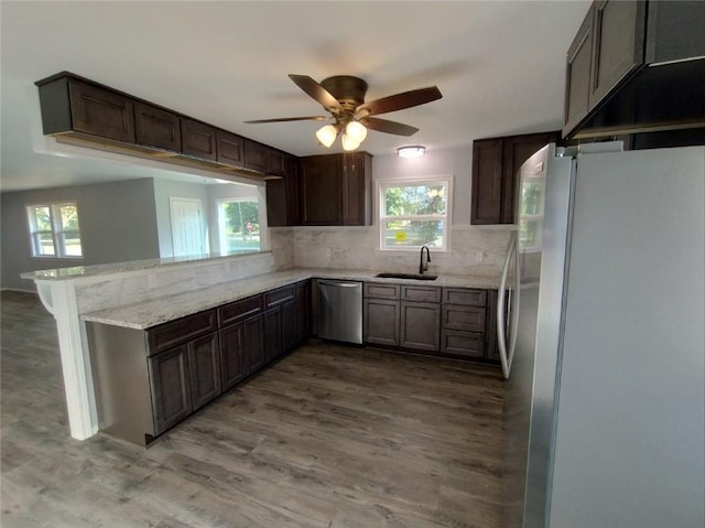 kitchen featuring light wood-type flooring, tasteful backsplash, stainless steel appliances, light stone countertops, and ceiling fan