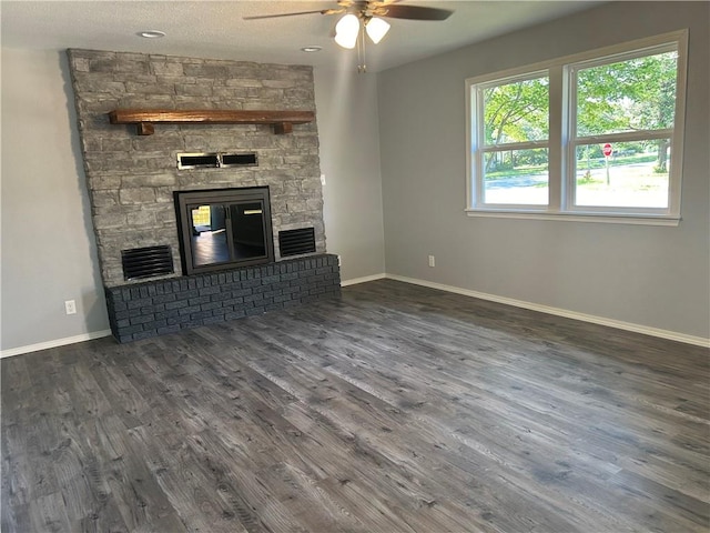 unfurnished living room with dark hardwood / wood-style floors, a textured ceiling, ceiling fan, and a stone fireplace